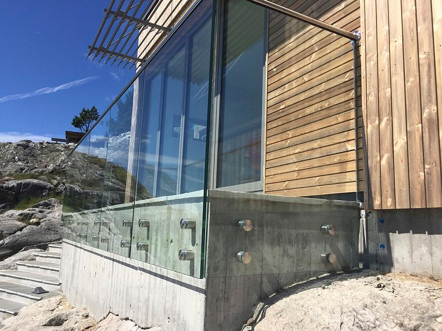 Hjørne av en hytte i glass og tre på svaberget