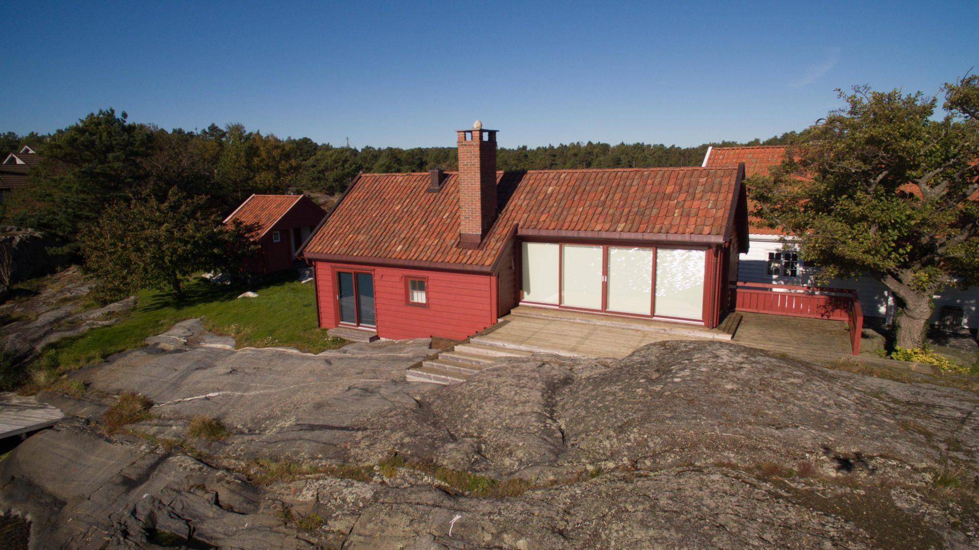 Rød dobbelgarasje med teglstein på taket, sett fra luften