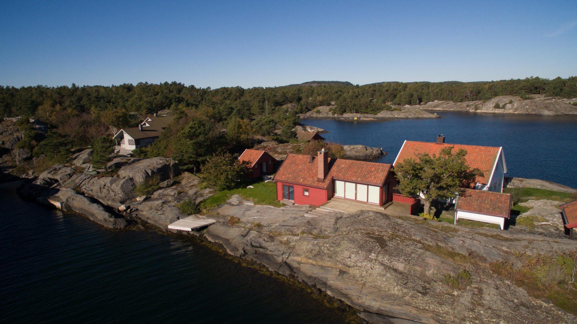Røde hus på en odde i skjærgården, sett fra luften